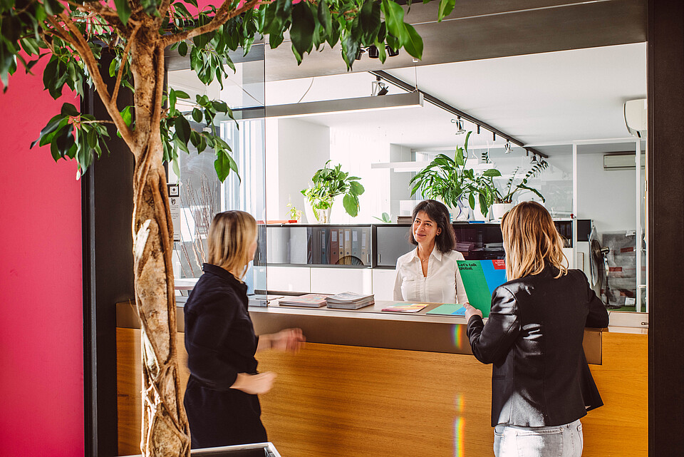A receptionist talking to two women at a desk 
