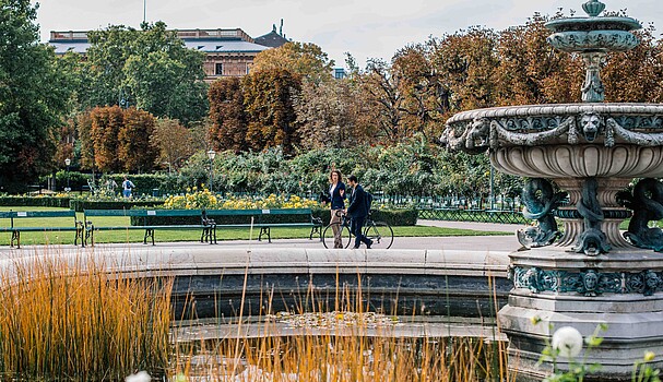 Man and woman walking by a fountain in park